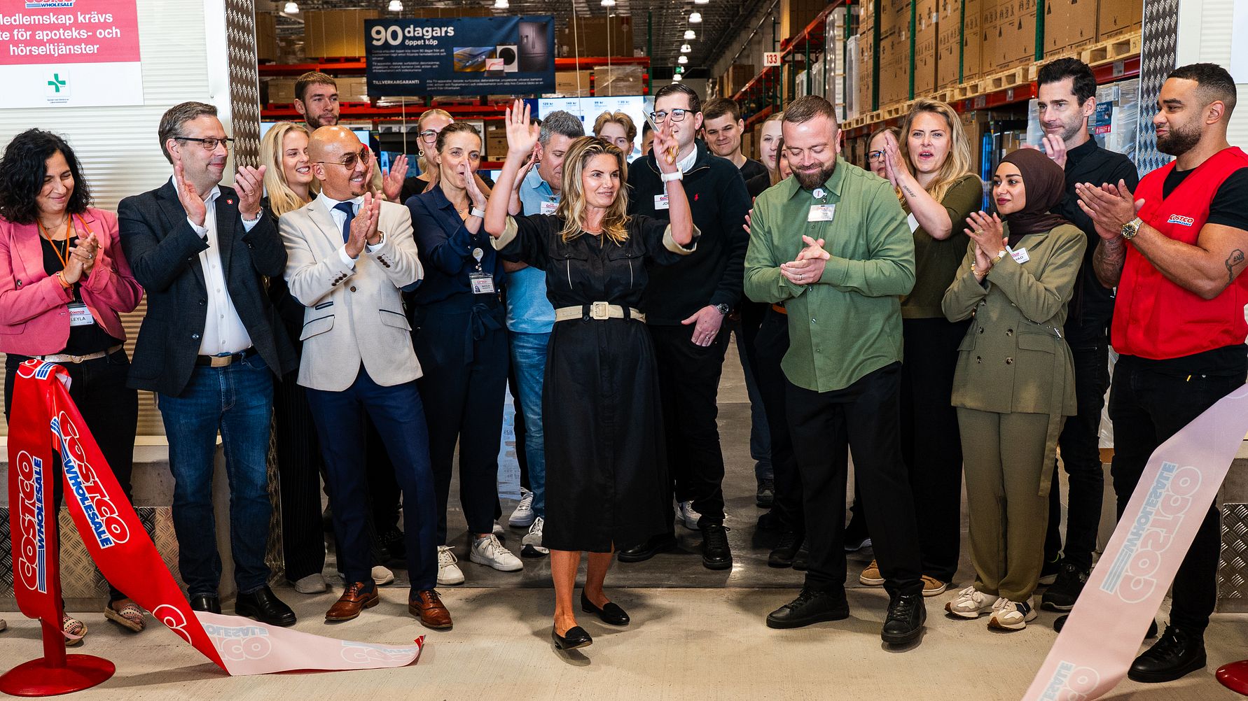 En grupp människor som står runt varandra och firar efter att ha klippt ett öppningsband.