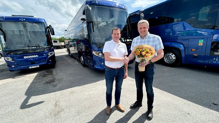 BLOMSTER: Scanias busselger Tore Aasgaard kunne overrekke en blomst sammen med de tre nye bussene til adm.dir. i JVB Helge Kvame. 