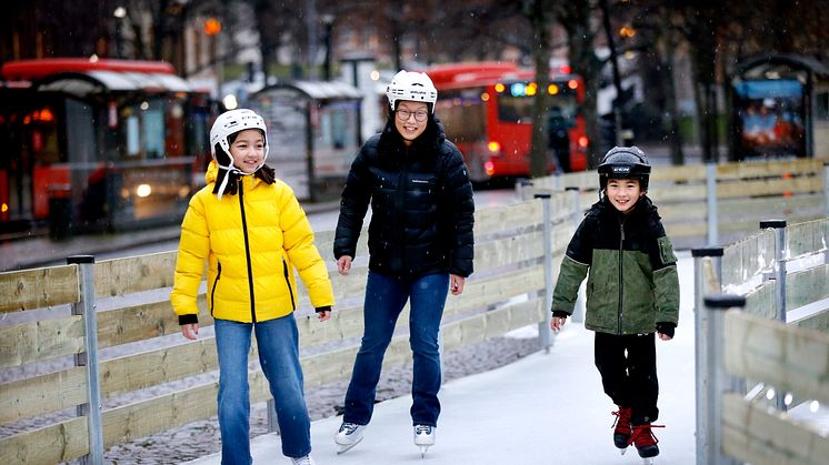 Kvinna och två barn åker skridskor på isbanan på Stora Torget.