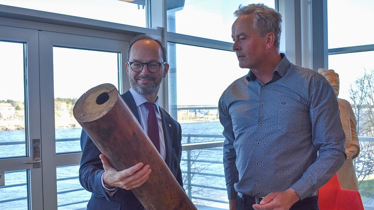 Infrastrukturministern Tomas Eneroth och Vakins VD Tomas Blomqvist tittar på en vattenledning i trä som användes fram till början av 1900-talet.