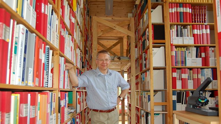 På bilden står Sven Werner i sitt omfattande forskningsarkiv. Han är professor emeritus i energiteknik och knuten till Högskolan i Halmstad.