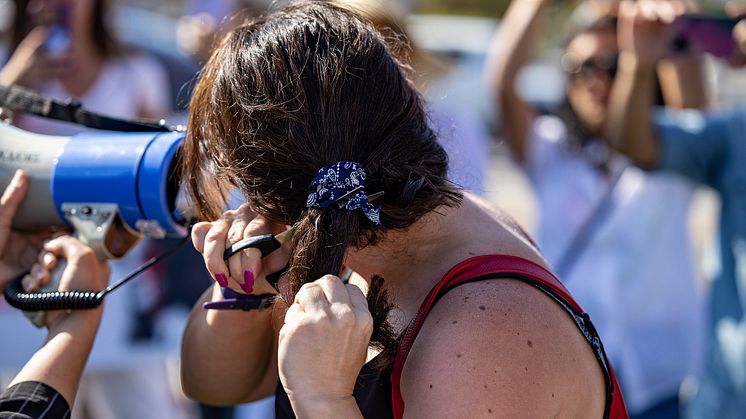 En kvinna klipper av sig håret i protest (foto: Brett Morrison, Creative Commons)