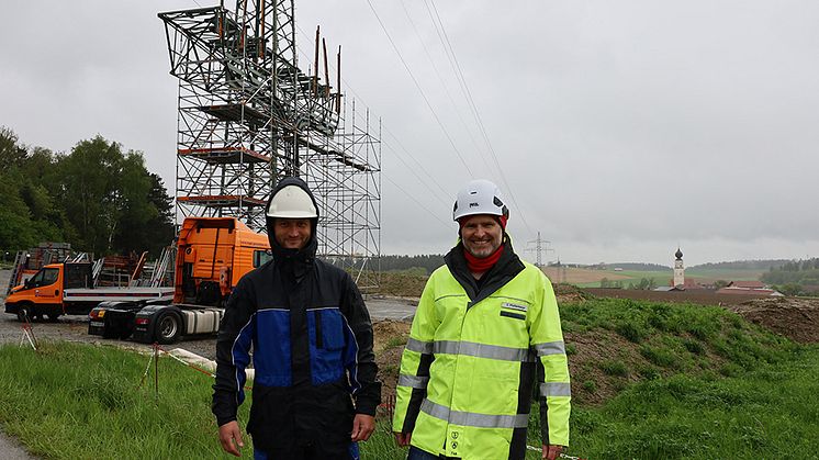 Bauleiter Claus Pfaffenberger (r.) und Baukontrolleur Norbert Radlmaier vor dem Übergangsmast. Hier wird das neue Hochspannungskabel vom Umspannwerk Tann mit der bestehenden Freileitung verbunden.