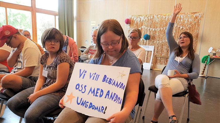 Deltagaren Klara Lüning håller upp en skylt med texten "Vi vill beblanda oss med andra ungdomar!". I bilden syns även deltagarna Axel Tapper, Moa Hallner och Camilla Berg Wolsink. 