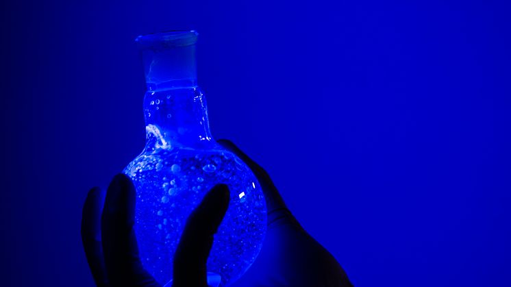 A solution of the new molecule glowing under UV light