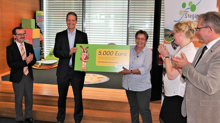 Den Kinderbibliothekspreis überreicht Ingo Schroers vom Bayernwerk an Bibliotheksleiterin Cornelia Kempgen (mi.). Pfarrer Walter Ries (li.), Dr. Claudia Pecher vom St. Michaelsbund (2. v.r.) und Bürgermeister Thilo Wagner gratulieren.