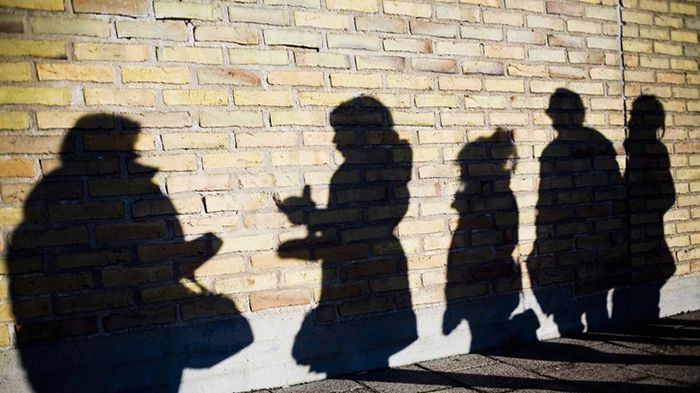 Alla som söker kulturstöd från Stockholms läns landsting måste intyga att de arbetar mot sexuella trakasserier. Foto: Maskot bildbyrå. Syntolkning: skuggor mot tegelvägg av människor i kö.
