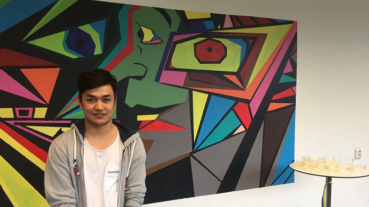 Mohamad framför sin målning som nu sitter på väggen i Lundenskolans entré. Foto: Jessica Ohliw