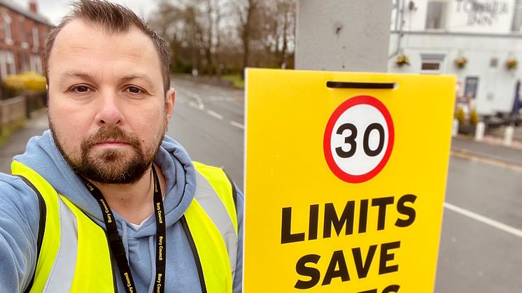 Cllr Kevin Peel installs one of the new road signs in Walmersley Road, Bury.