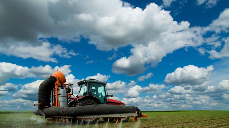 Tractor spraying soybean crops field at spring season, often using herbicides, which may leech through the soil into water sources below and possibly end up in human or animal drinking water.