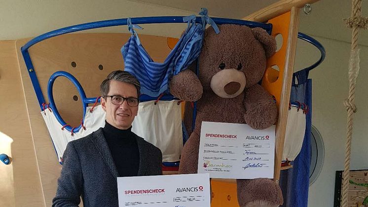 Oliver Just, Geschäftsführer der Avancis GmbH, präsentiert die beiden Spendenschecks im Geschwisterzimmer des Kinderhospizes