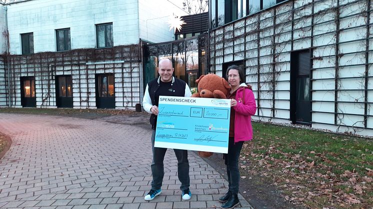 André Neudert präsentiert den gewaltigen Spendenscheck mit Kerstin Stadler von Bärenherz vor dem Kinderhospiz