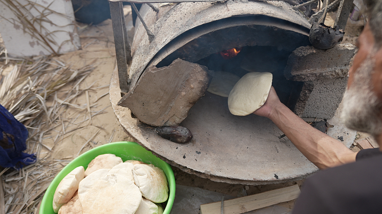 Mutaz använder ugnen de byggt av lera för att göra bröd. Foto: Alef Multimedia/Oxfam