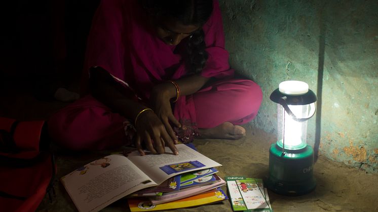Aarathi läser läxan i ljuset av sin solcellslampa