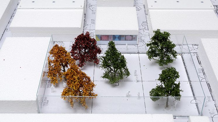 Syntolkning: modell av sjukhusbyggnad med utomhusgård, modellträd och huskroppar. På en väggyta syns placering av tänkt konstverk.  ©Anne Ingeborg Birginvad/Bildupphovsrätt 2018