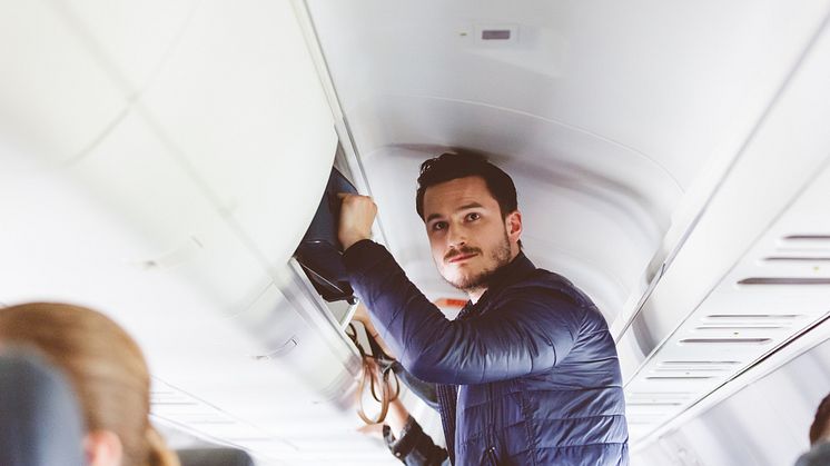 THEME_TRAVEL_AIRPORT_AIRPLANE_PEOPLE_MALE_PASSENGER_STORING_HAND_LUGGAGE_IN_THE_OVERHEAD_LOCKER_GettyImages-846448616_Universal_Within usage period_99793