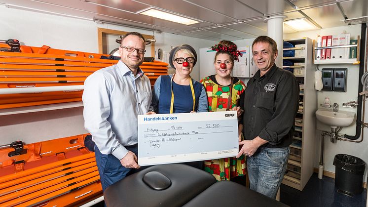 Jan Heimbürger, Fleet Personel Officer (left) and sailor Lars Christensen, handed a cheque for 52,500 Danish kroner to hospital clowns, Fiola (left) and Sally 52.500 at the ship’s hospital on board the ‘Esvagt Cobra’. 