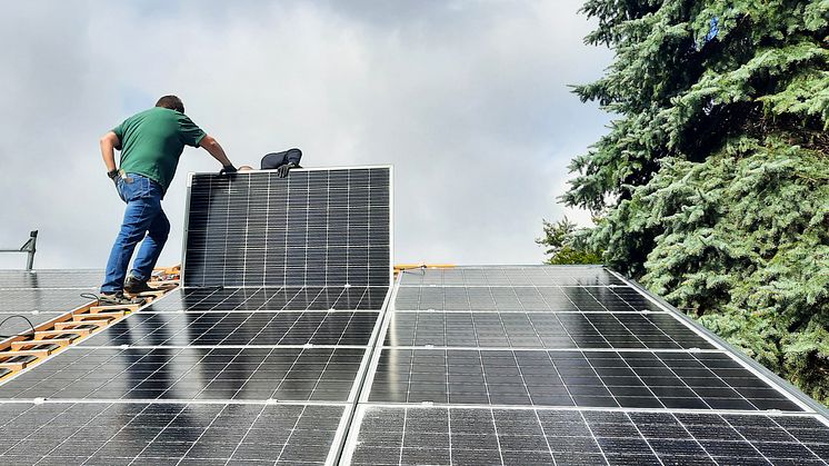 Zwei Menschen montieren eine Photovoltaik-Anlage auf dem Dach eines Hauses
