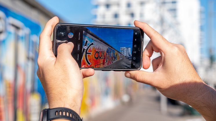 Berlin_Person_macht_ein_Handyfoto_von_Berliner_Mauer_mit_Eastside_Gallery