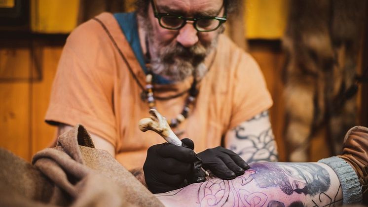 Tatuerare som tatuerar med historiska verktyg. Foto Zaneta