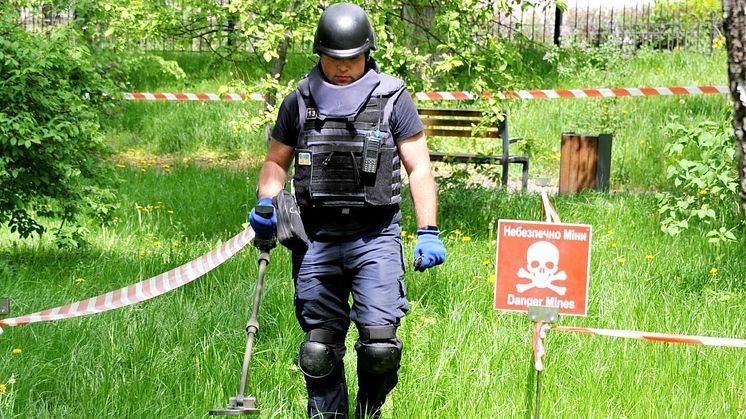 An employee of the State Emergency Service of Ukraine sweeps an area of ground for unexploded ordnance and landmines