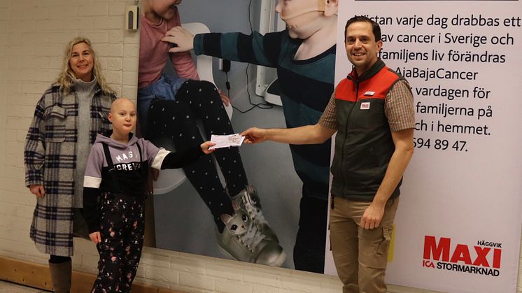 10 åriga Alice som behandlas för cancer och hennes mamma Sophie tar emot det första presentkortet i projektet "I Care AjaBajaCancer" av Roger Holgersson, butikschef ICA Maxi Stormarknad Häggvik.