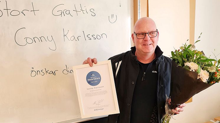 Conny Karlsson som är besiktningstekniker på stationen i Örebro-Lillån har utsetts till månadens medarbetare i Bilprovningen. På bilden gratuleras han med blommor och diplom.