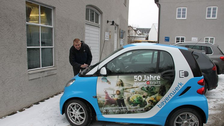 Mit dem „50 Jahre Jugend forscht E-Smart“ trifft das Patenunternehmen Bayernwerk ehemalige bayerische Preisträger, hier Jürgen Geist, und lässt diese das Elektroauto signieren.