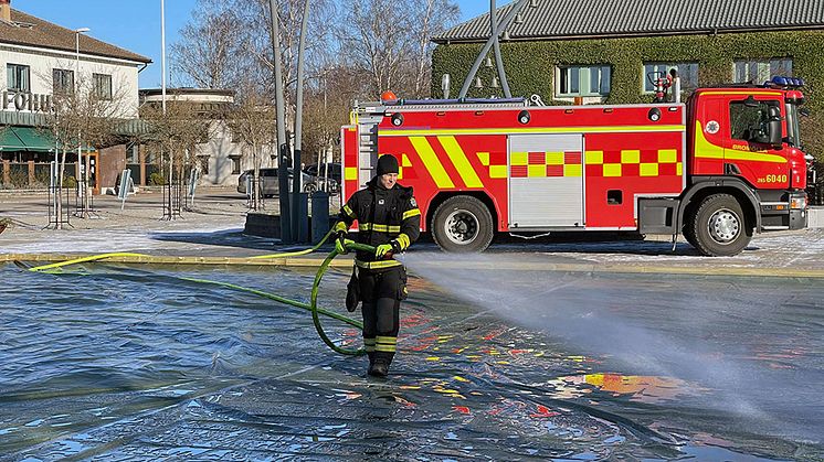 Räddningstjänsten spolar det första vattnet på isbanan vid torget i Bromölla.