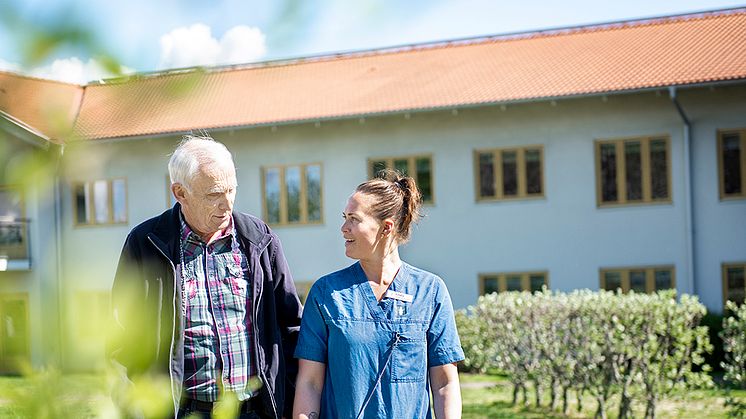 Anställd promenerar och pratar med omsorgstagare.