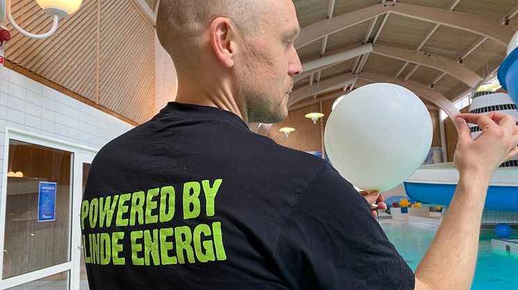 Fredrik Klingvall, kommunikationsansvarig på Linde energi, tar hjälp av nål för att spräcka hål på aprilskämtet. Foto: Linde energi