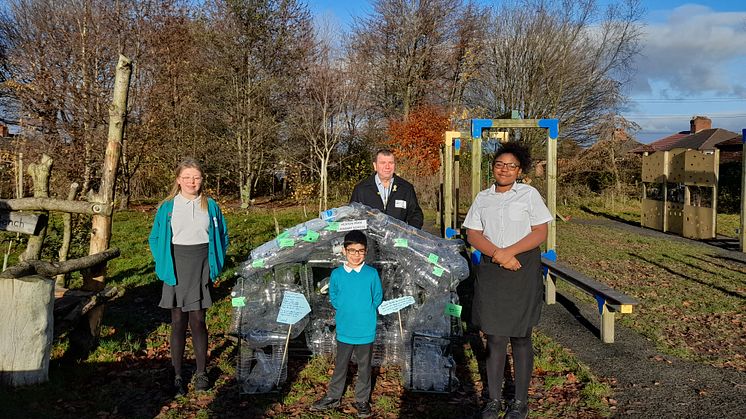 Cllr Alan Quinn with students from Heaton Park Primary school in front of their greenhouse artwork made of plastic bottles
