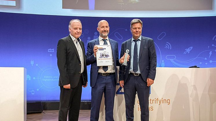 Bundeswirtschaftsminister Robert Habeck (rechts) und ZVEI-Präsident Dr. Gunther Kegel (links) übergeben Daniel Hager, CEO der Hager Group des Electrifying Ideas Award des ZVEI.