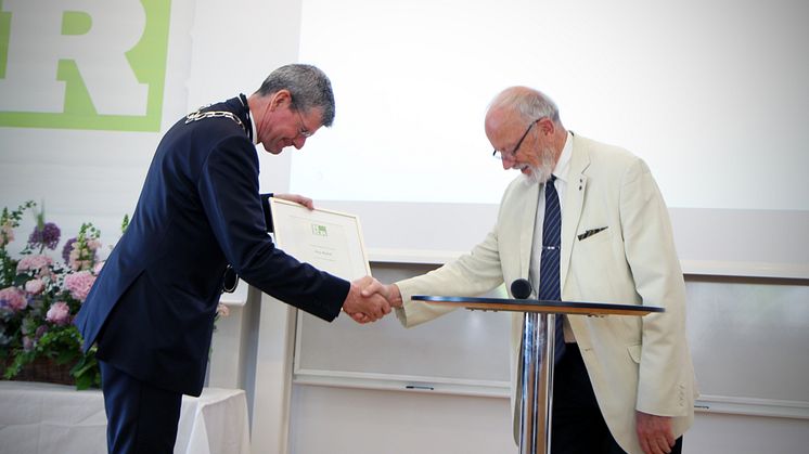 Rektor Håkan Pihl lämnar över nyinstiftade hedersutmärkelsen Rector Emeritus Maximus till högskolans förste rektor Kaj Björk.