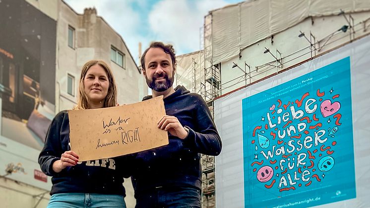 Katharina Gerland (Viva con Agua) und Marc Schachtel (Parship) vor einem der Riesenbanner in Hamburg.