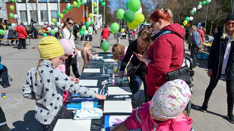 Tiina Herttua koostaa seinänkokoisen taideteoksen työpajoissa maalatuista laatoista.