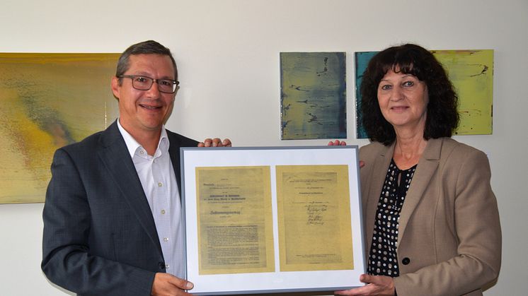 Kommunalbetreuer Frank Schneider übergab eine gerahmte Kopie des ursprünglichen Vertrags an Bürgermeisterin Helga Schmidt-Neder.
