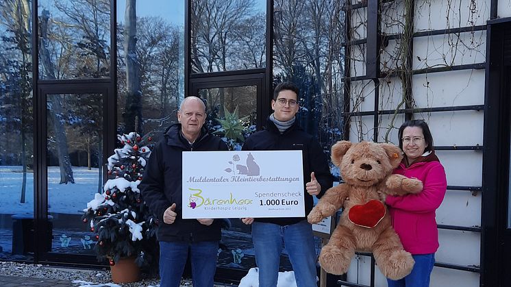 Karlheinz und Tim Latotzke präsentieren stolz mit Kerstin Stadler vom Bärenherz ihren Spendenscheck vor dem Kinderhospiz
