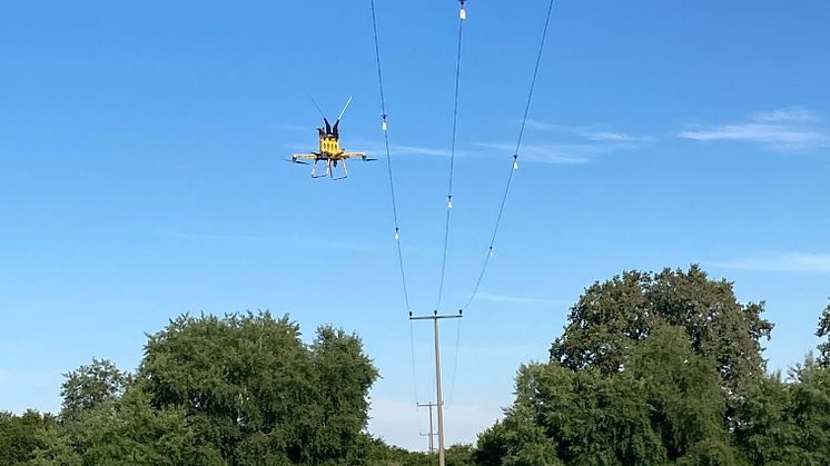 Im Abstand von zirka 10 Metern werden die Vogelschutz-Marker in die Leitung eingehängt. Mit einer Drohne können sie auch in schwer zugänglichen Bereichen wie hier an der Freileitung bei Burgheim ohne großen Aufwand installiert werden (LEW)