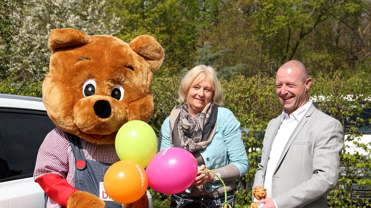 Elvira Wegner vom Kinderhospiz mit Christian Pohlers, Markenverantwortlicher von Suzuki in der Markkleeberger Autohaus Dinnebier Filiale und Suzuki Maskottchen Disu. Der Name des Bären ist aus den Begriffen Dinnebier und Suzuki entstanden.