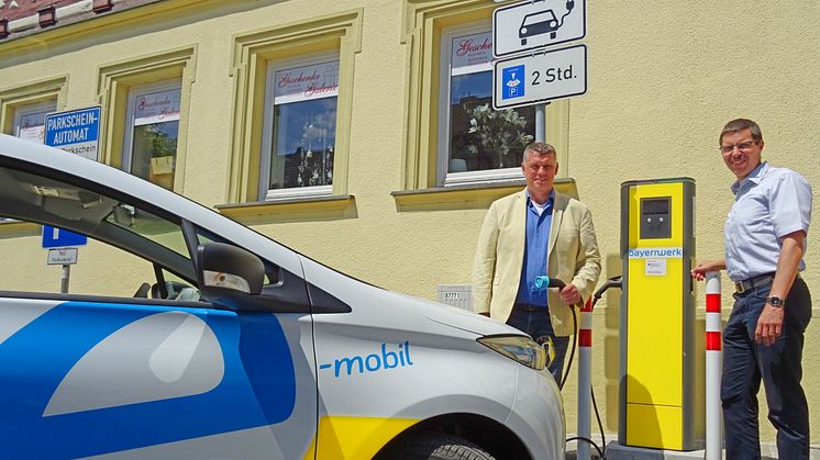 Zweiter Bürgermeister Hans-Josef Stich (l.) und Bayernwerk-Kommunalbetreuer Burkhard Butz nehmen die neue Stromtankstelle auf dem Marktplatz in Bad Staffelstein offiziell in Betrieb.