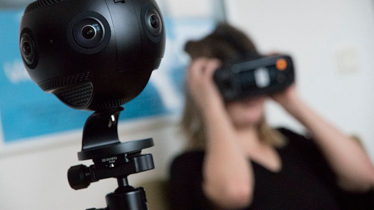 Syntolkning: VR-kamera i förgrunden och en person med VR-glasögon i bakgrunden. Foto Mikael Ström