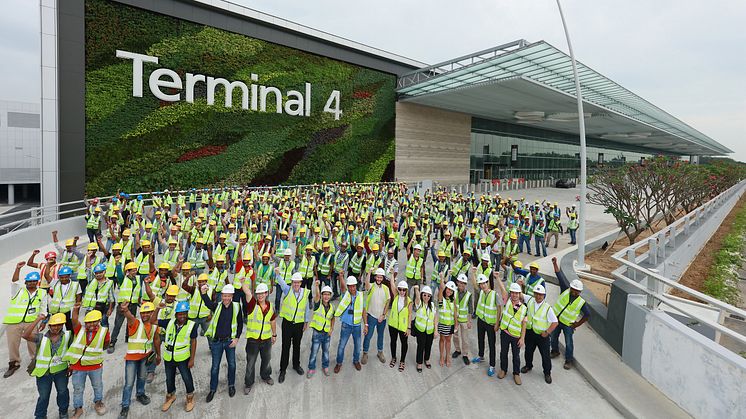 Airport staff and workers gather at Changi Airport's Terminal 4 facade to mark the completion of construction