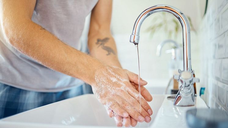 Person tvättar händerna i handfat 