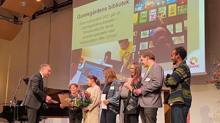 Magnus Lunderquist, ordförande i kulturnämnden Region Skåne delar ut priset till Alma Abuzarad, Edina Cosabic, Ilona Geiger, Sarah Granholm och Alva, Alexander Magnusson och Hassan Ali Mahmoud