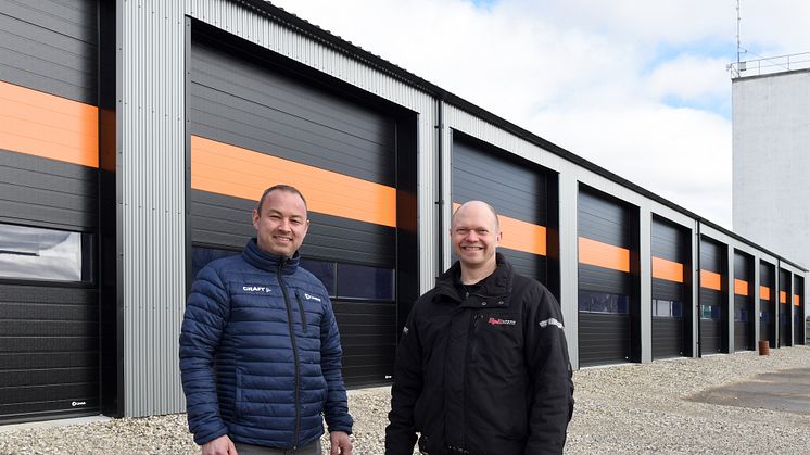HPH Totalbyg har opført Djurs Kloakservices nye bygninger, og Lindab har leveret en helt særlig port med orange striber. Anders Godsk fra Lindab (tv.) og byggeleder Palle Simonsen fra HPH Totalbyg (th.)