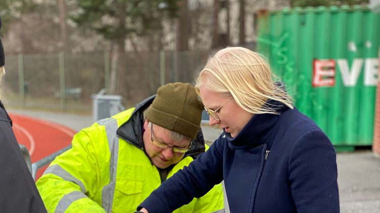 Idrottsborgarråd Karin Ernlund (C) inspekterar en granulatfälla vid Hammarbyhöjdens bollplan. Med en grönblå miljonsatsning ska 50 idrottsanläggningar förses med granulatfällor under 2020 för att minska mikroplaster i Stockholms vatten.
