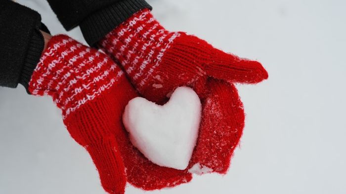 Händer i vantar som håller ett snöhjärta.