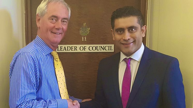 Cllr David Jones (left) is welcomed as the new council leader by Cllr Rishi Shori.