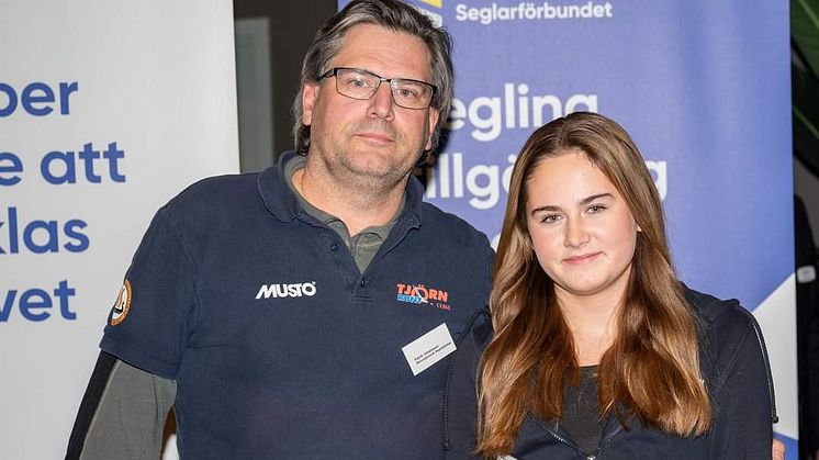 Patrik Johansson, arrangemangsansvarig för Junior-SM i segling 2023, tar emot Stenungsunds segelsällskaps hedersomnämnande tillsammans med dottern Olivia på Seglarträffen i Mölndal. 